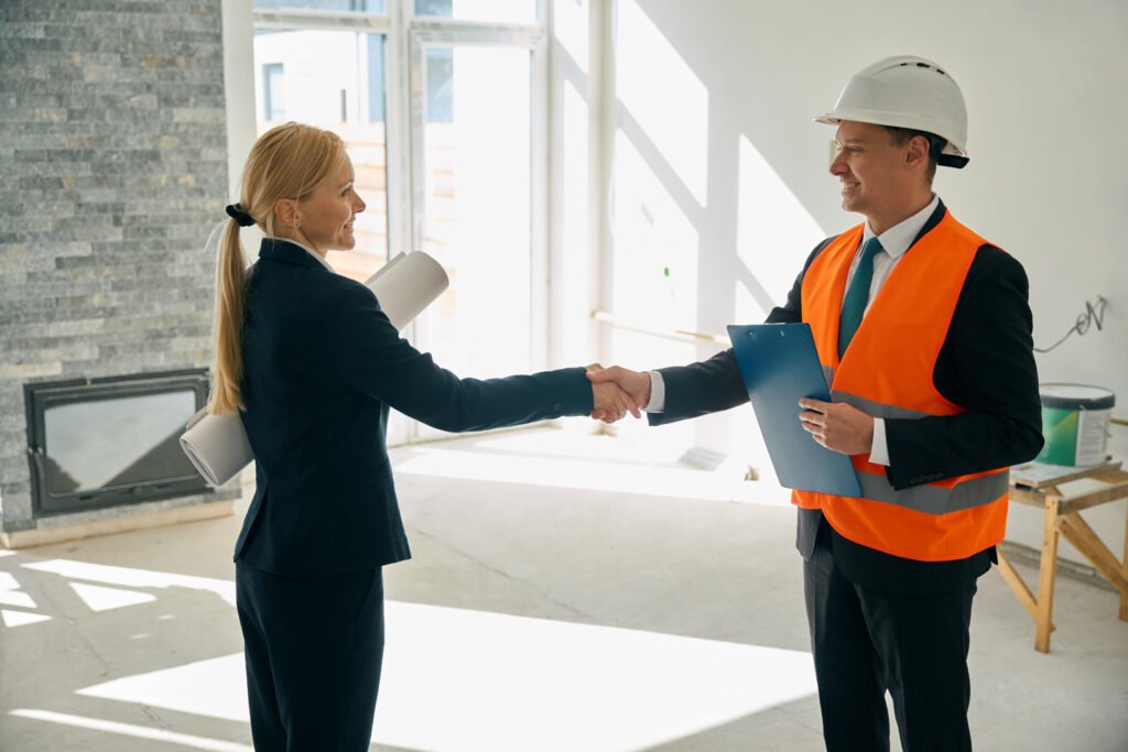 Woman and foreman standing in room and shaking hands - Mallin Contracting